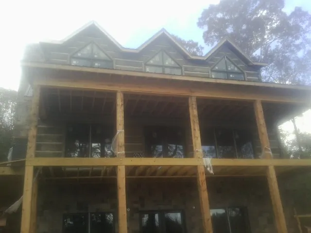 Dormers and porch framing on a large log home under construction — Roof Coating work by our crew in Plains