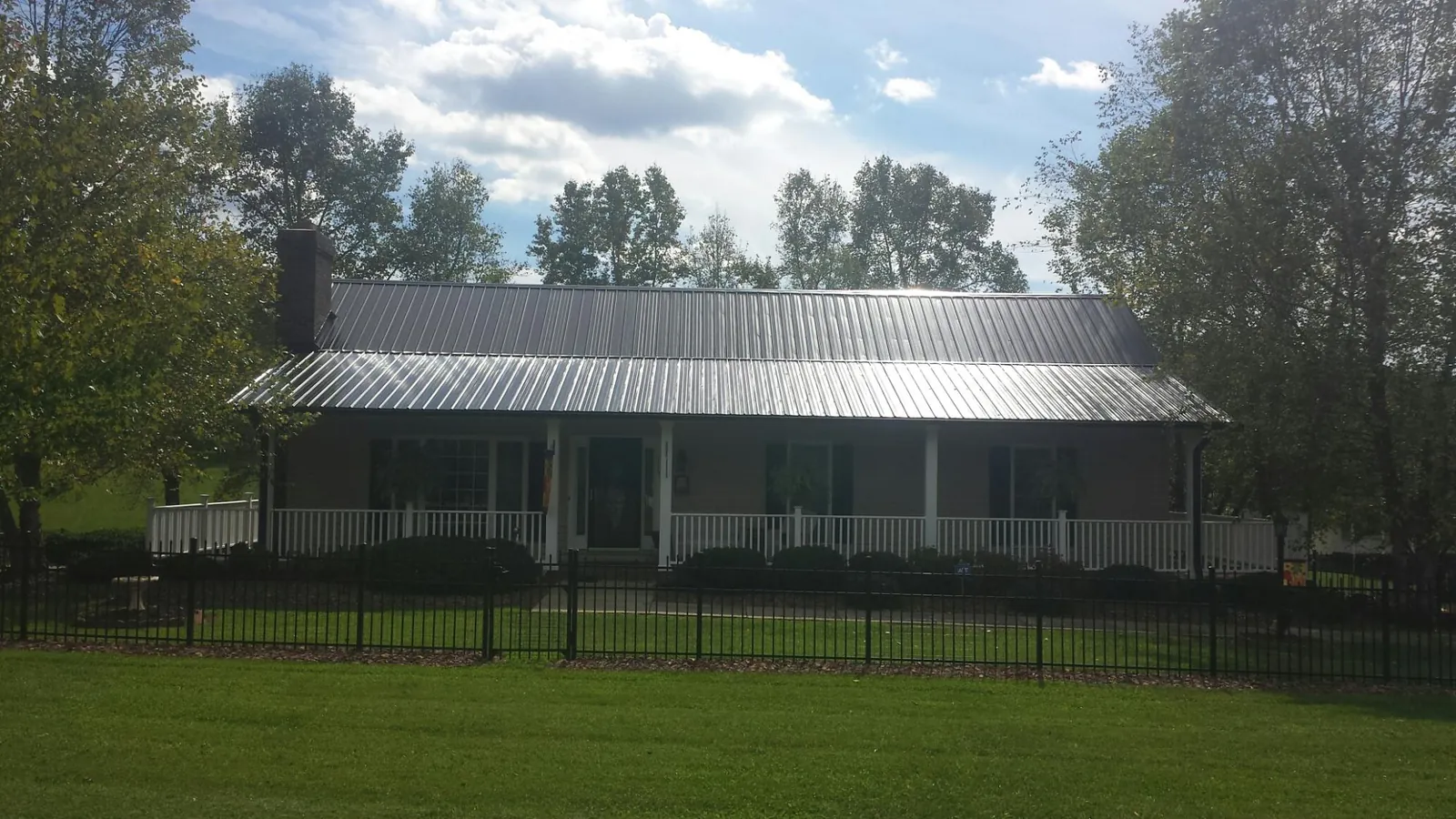 Gray metal roof on a brick ranch with a full width front porch — Gutter Guard Installation work by our crew in Plains