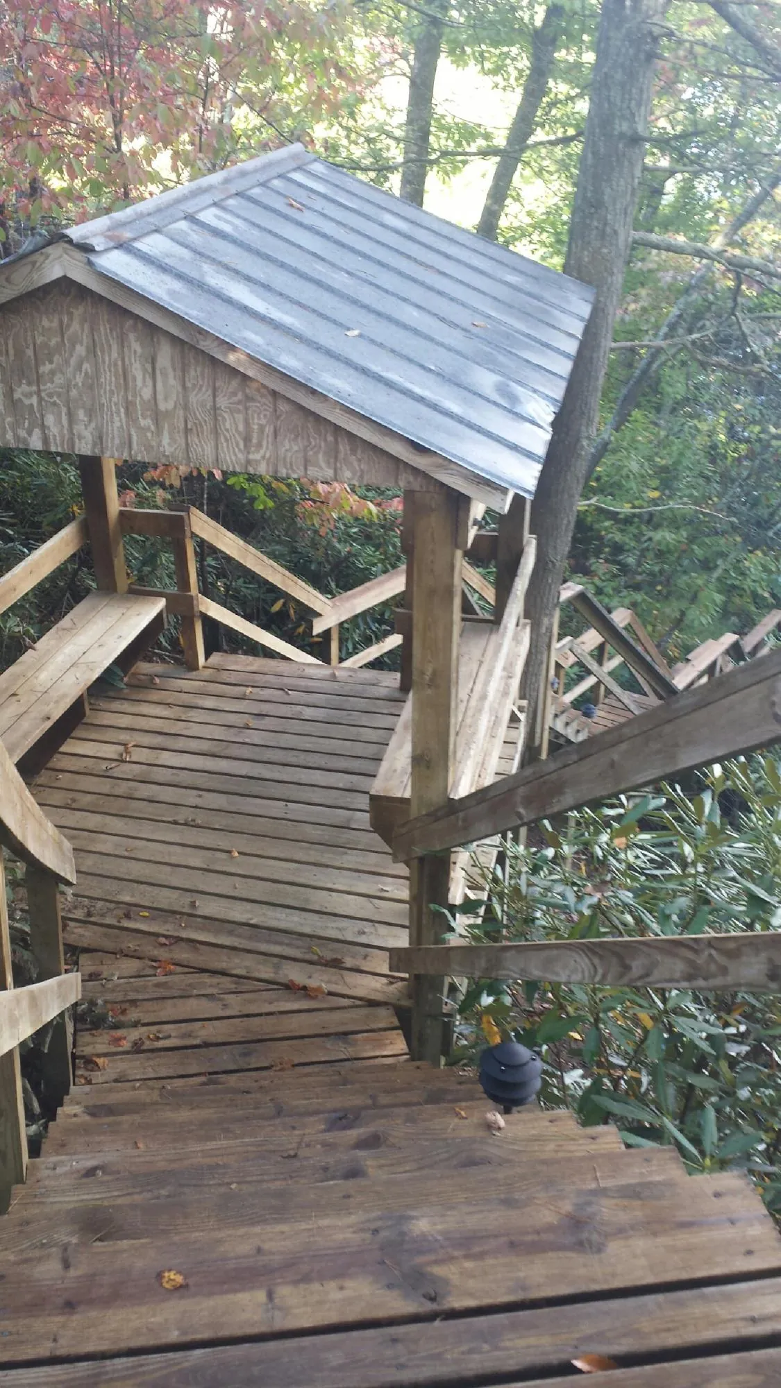 Metal roofed shelter over wooden steps on a wooded walkway — Skylight Repair & Installation work by our crew in Plains